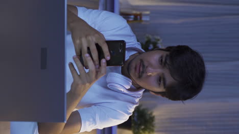 Vertical-video-of-The-man-who-texts-on-the-phone-at-home-at-night-is-disappointed.